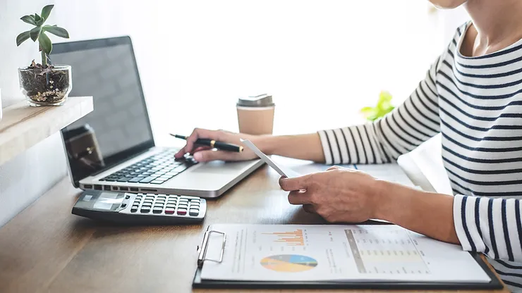 Accountant calculating figures with documents and laptop.
